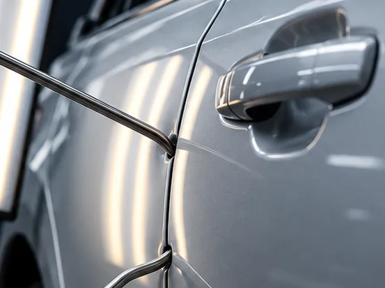 Technician using a PDR rod and light board to remove a door dent at Glenbard Auto Body in Lombard, IL